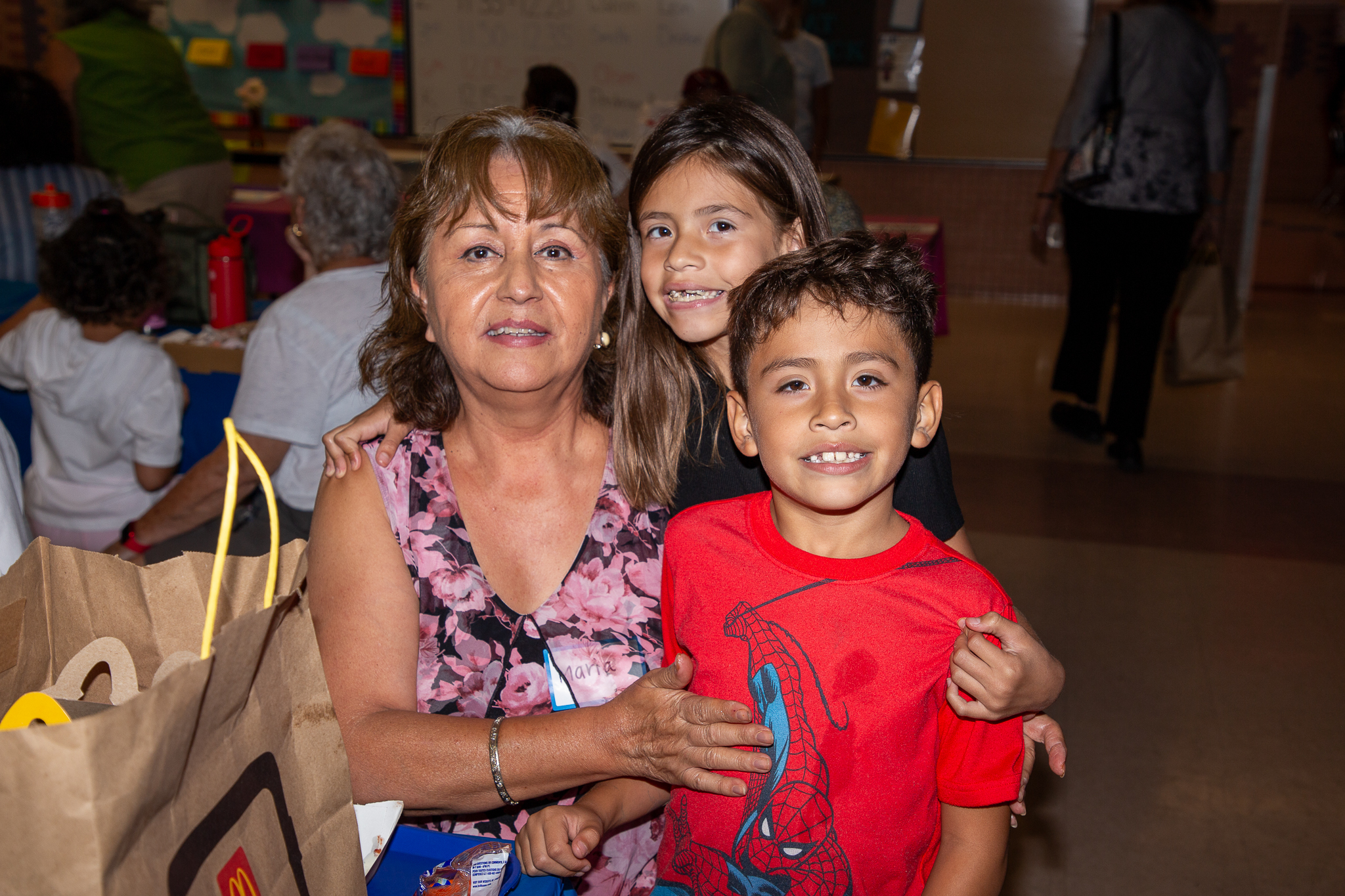 A grandmother smiles with her granddaughter and grandson