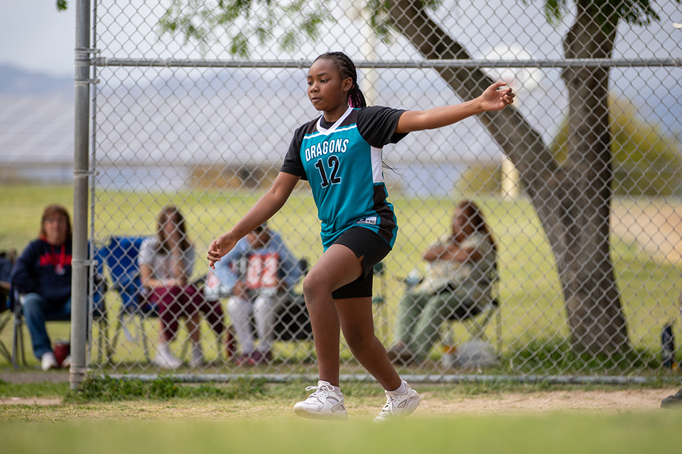 A girl in a teal jersey runs out to get ready to kick the ball