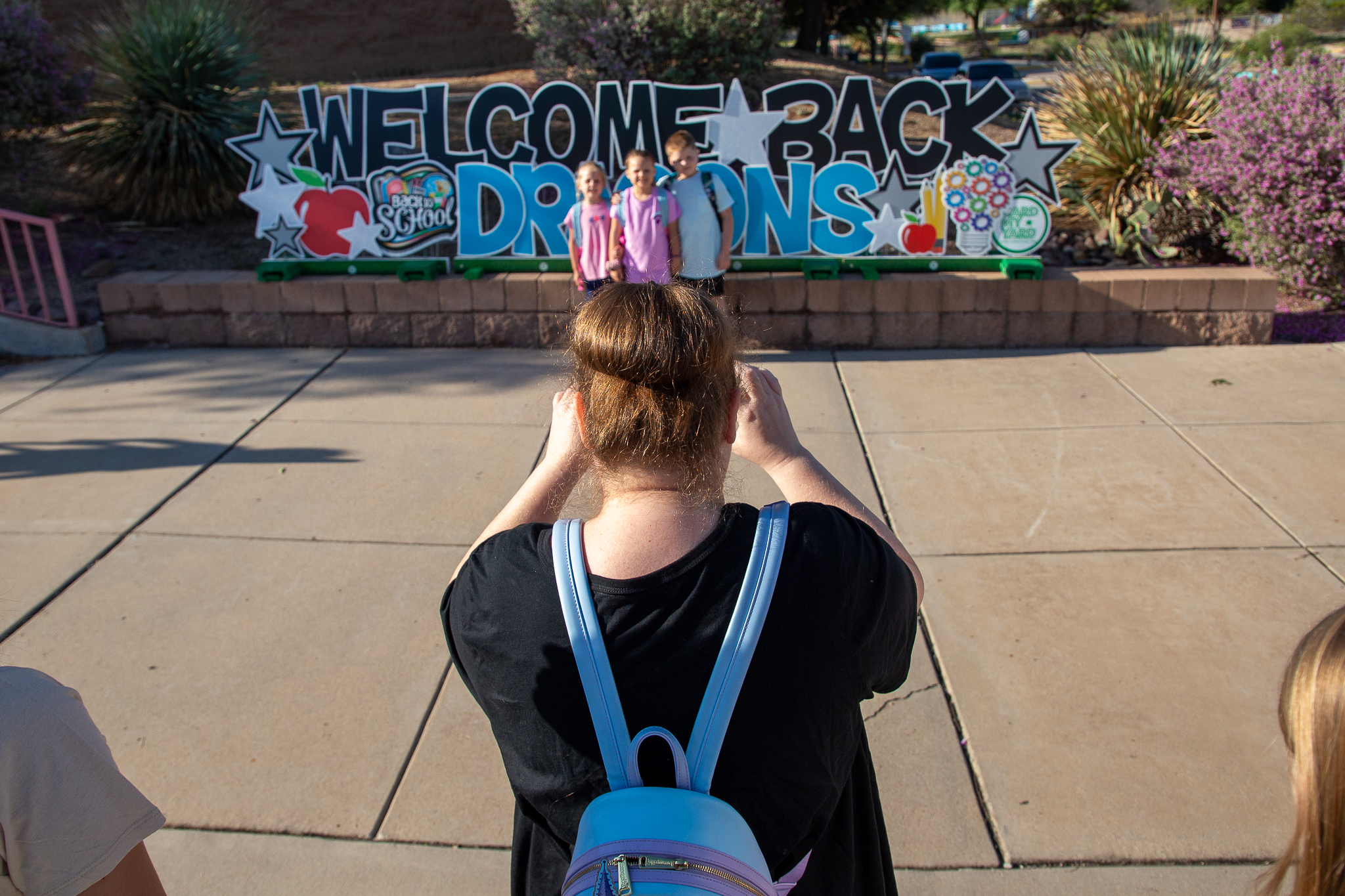 A mom takes a photo of her three kids in front of the Welcome Back Dragons sign