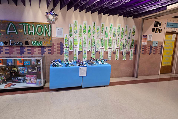 A wall, display case and table showing off art projects