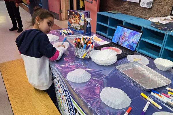 A little girl looks over her shoulder as she draws on a coffee filter