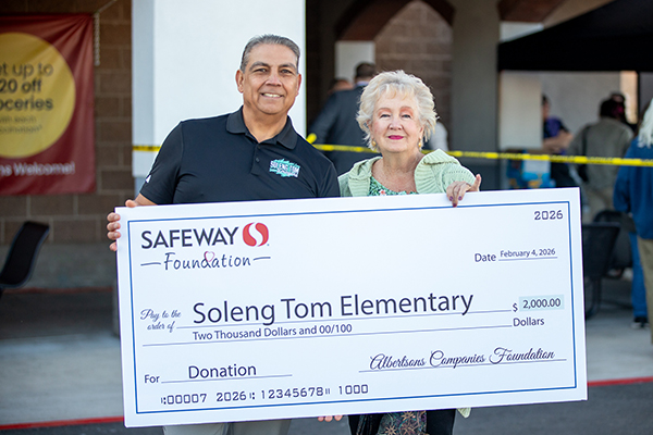 A man and woman from Soleng Tom hold up the giant check from Safeway Foundation